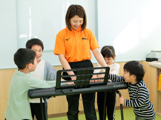 指導者が電子ピアノを弾いている様子