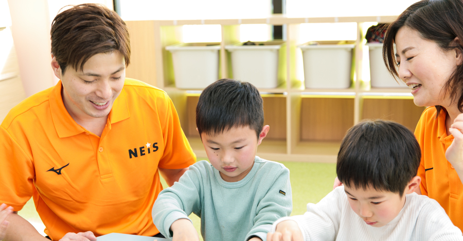 指導者と子どもたちが机で学習に取り組んでいる様子