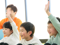 指導者と子どもたちが一緒に手を挙げて活動している様子