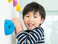 子どもがボルダリングの壁をつかんで遊んでいる様子