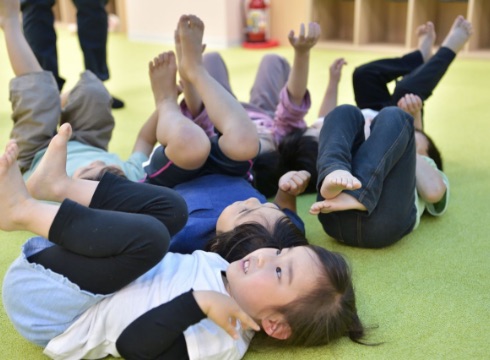 子どもたちが床に寝転んで体を動かしている様子
