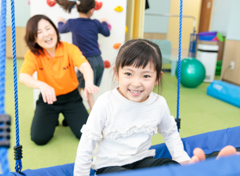 笑顔の子どもが先生と一緒に運動している様子