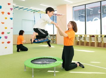 トランポリンに挑戦する子どもと体操指導員のサポート
